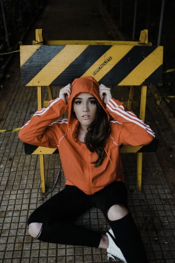 Woman Sitting on Floor in Front of Yellow and Black Road Signage