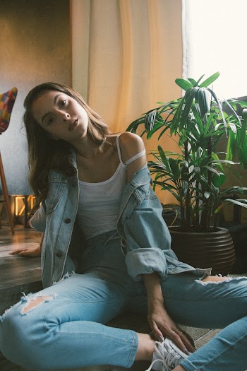 Woman Sitting On Floor Near Green Leaf Potted Plant