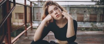 Woman Sitting on Floor Near Red Metal Railings