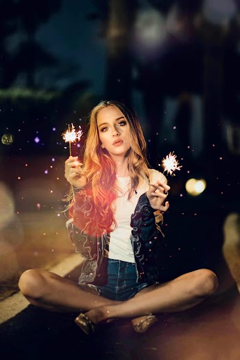 Woman Sitting On Floor While Holding Sparklers