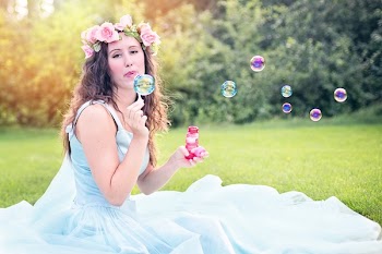 Woman Sitting on Grass Blowing Bubbles