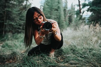 woman sitting on grass field while taking photo