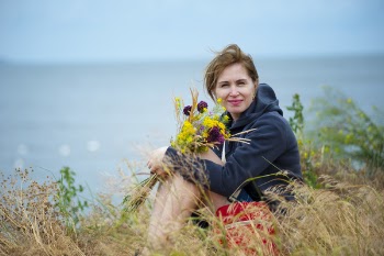 Woman Sitting on Grass Holding Flowers Wearing Black Hoodie