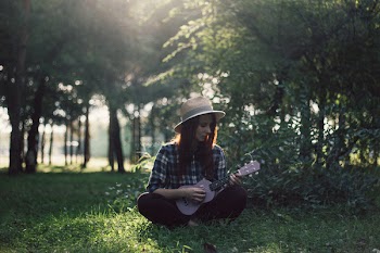 Woman Sitting on Grass Playing Ukulele