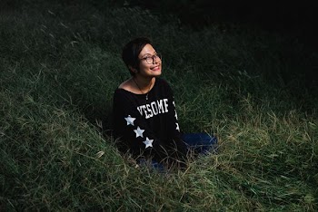 woman sitting on grass smiling and looking up during nighttime