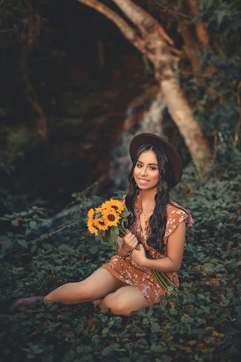 Woman Sitting on Grass While Holding Sunflower
