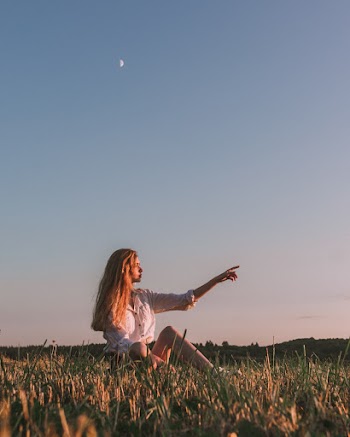 Woman Sitting on Grasses Pointing Her Finger