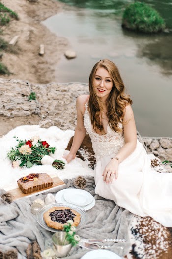 Woman Sitting on Gray and White Textile Beside Pie and Cake Near Body of Water