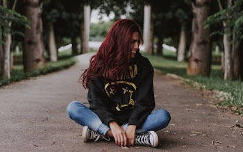 Woman Sitting on Gray Concrete Pavement