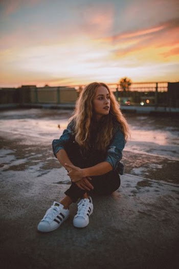 woman sitting on gray concrete pavement