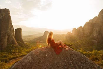 woman sitting on gray rock