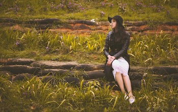 Woman Sitting on Gray Stone Barrier Near Green Grasses