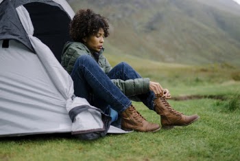 Woman Sitting on Gray Tent Tying shoe lace