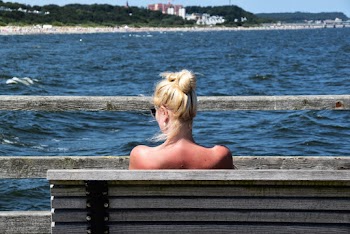 Woman Sitting on Grey Bench in Front of Body of Water