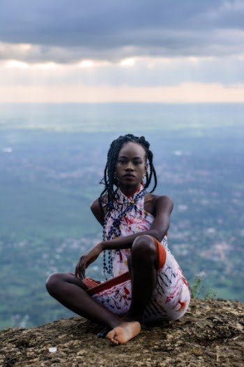 Woman Sitting on Ground and Village at Distance