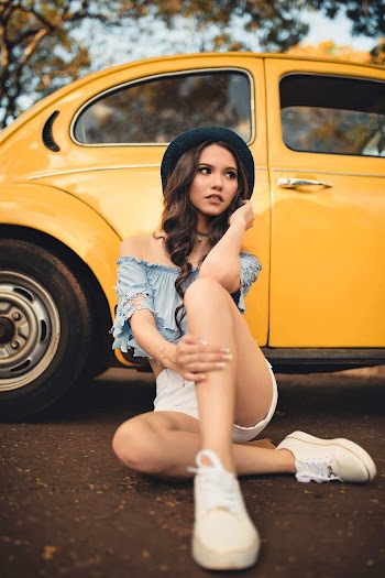 Woman Sitting on Ground Beside Yellow Vehicle