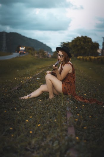 Woman Sitting on Ground Playing Guitar