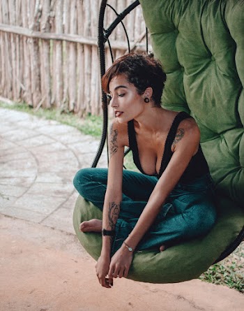 Woman Sitting on Hanging Egg Chair Near Wooden Fence