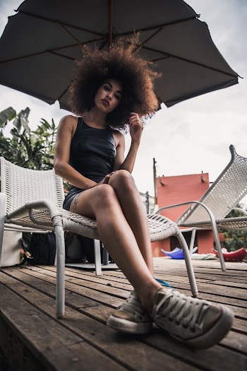 Woman Sitting on Lounger Under Umbrella