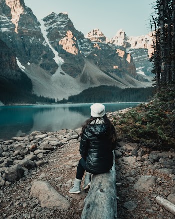 Woman Sitting on Lug Near Body of Water