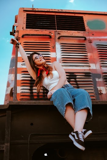 Woman Sitting on Orange and Gray Train Under Blue Sky