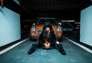 woman sitting on pavement near car