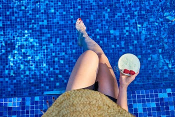 Woman Sitting on Poolside Holding Cocktail