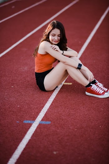 Woman Sitting On Red Track Field