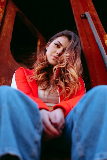 Woman Sitting on Red Truck While Looking Down