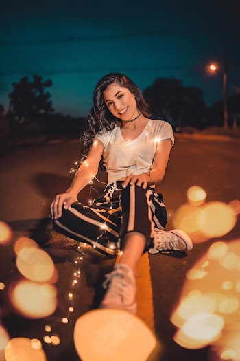 Woman Sitting on Road With String Lights during Night