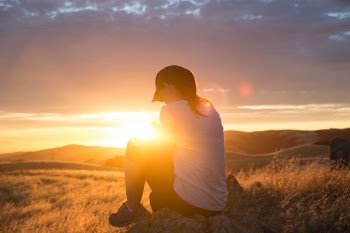 woman sitting on rock during golden hour