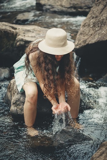 Woman Sitting on Rock Holding Water