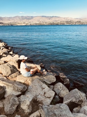 Woman Sitting on Rock Near Body of Water