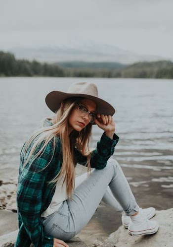 woman sitting on rock near body of water during daytime