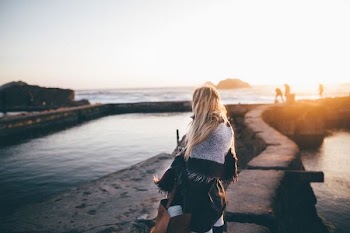 woman sitting on rock near lake