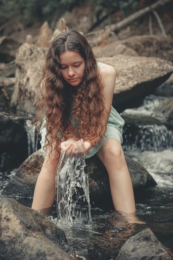 Woman Sitting on Rock on River