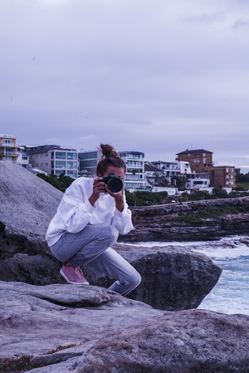 Woman Sitting on Rock While Taking Photo