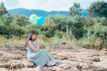 Woman Sitting On Rocks Holding Balloons