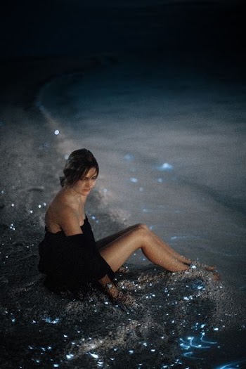 woman sitting on sand near seashore photo