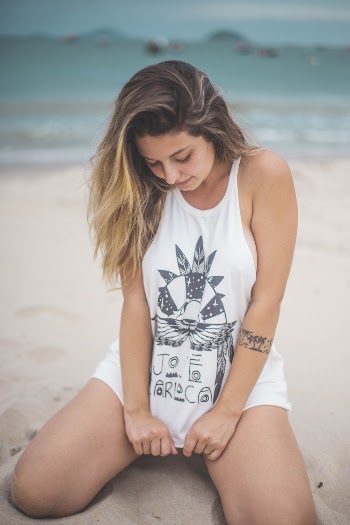 Woman Sitting on Seashore Wearing White Tank Top