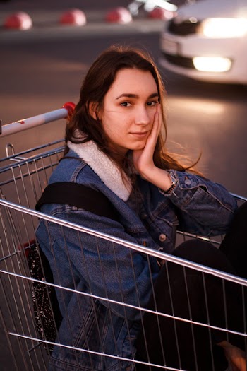 Woman Sitting on Shopping Cart