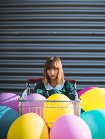 Woman Sitting on Shopping Cart