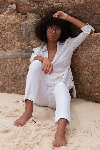 Woman Sitting on Shore While Leaning on Rock