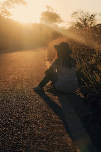 Woman Sitting On Side Of The Road