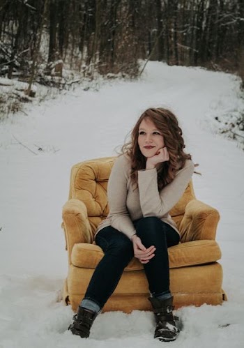woman sitting on sofa chair surrounded with snow and trees