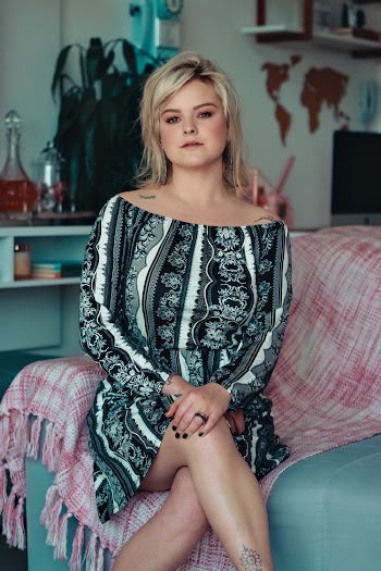 Woman Sitting on Sofa Wearing An Off Shoulder Dress