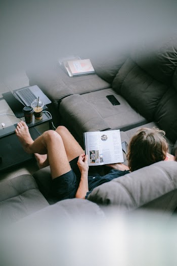 Woman Sitting on Sofa While Reading Book
