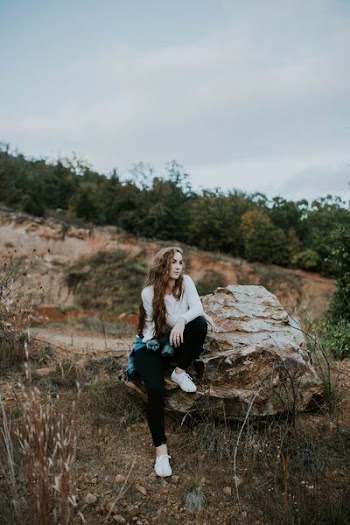 woman sitting on stone boulder outdoor