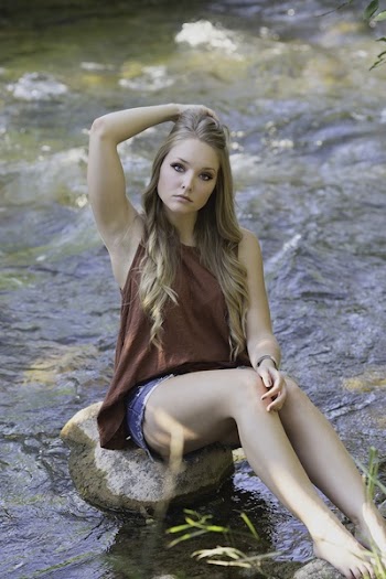 Woman Sitting on Stone Near Body of Water