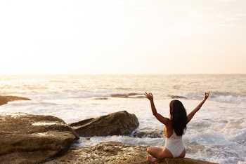 Woman Sitting on Stone Near Sea